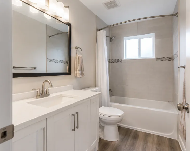 Completed bathroom with a white vanity, framed mirror and tiled tub surround