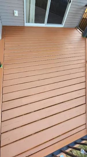 Deck after restoration: evenly stained deck boards along the house wall