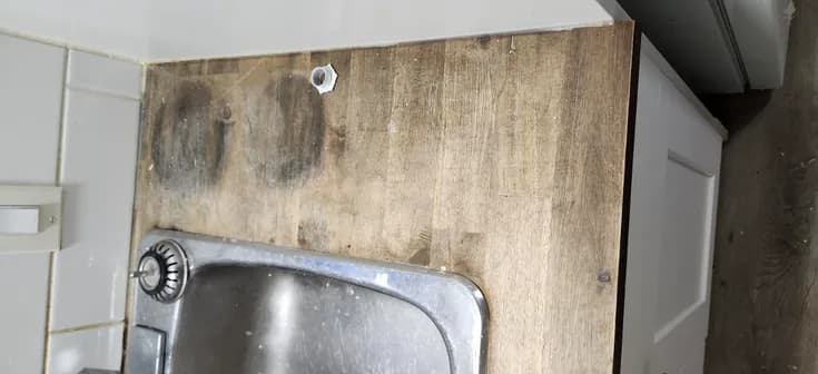 Kitchen before renovation: water-damaged laminate backsplash behind the sink